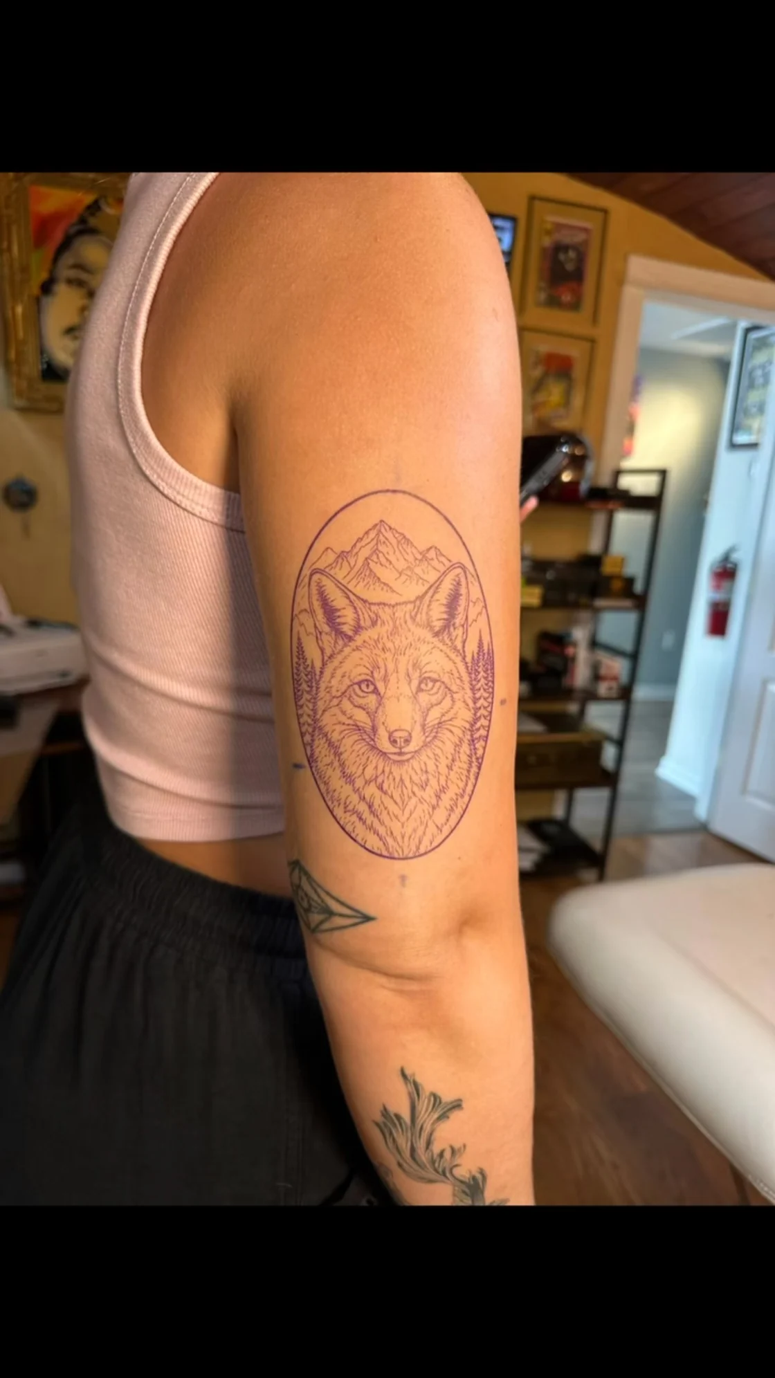 The poster shows a purple fox stencil inside an oval with mountains and trees on the upper arm; the video captures the tattoo in progress. Tattoo work by Brian of Vicious Ink.