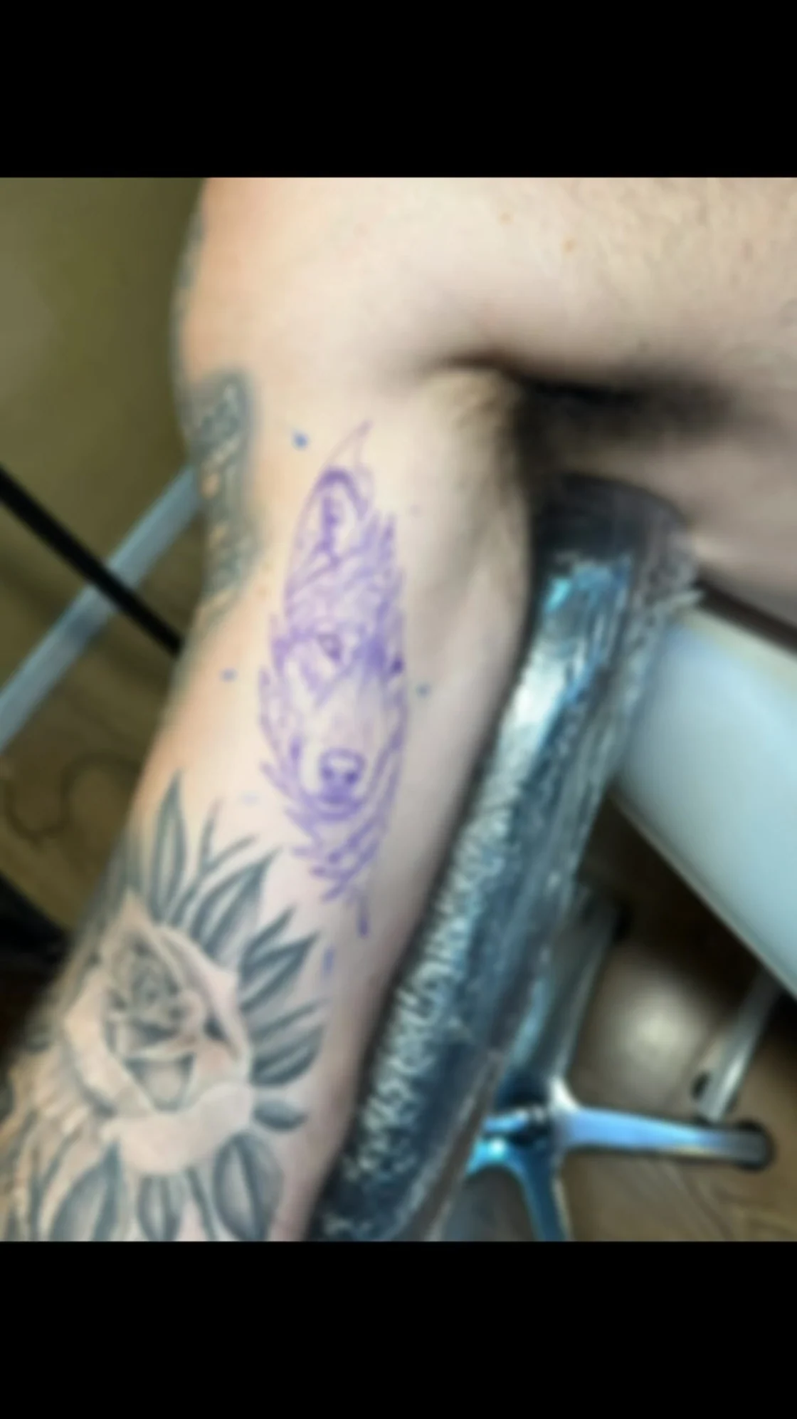 A blurred video poster shows a purple stencil or work in progress over existing floral tattoos, with limited detail available for display. Tattoo work by Brian of Vicious Ink.